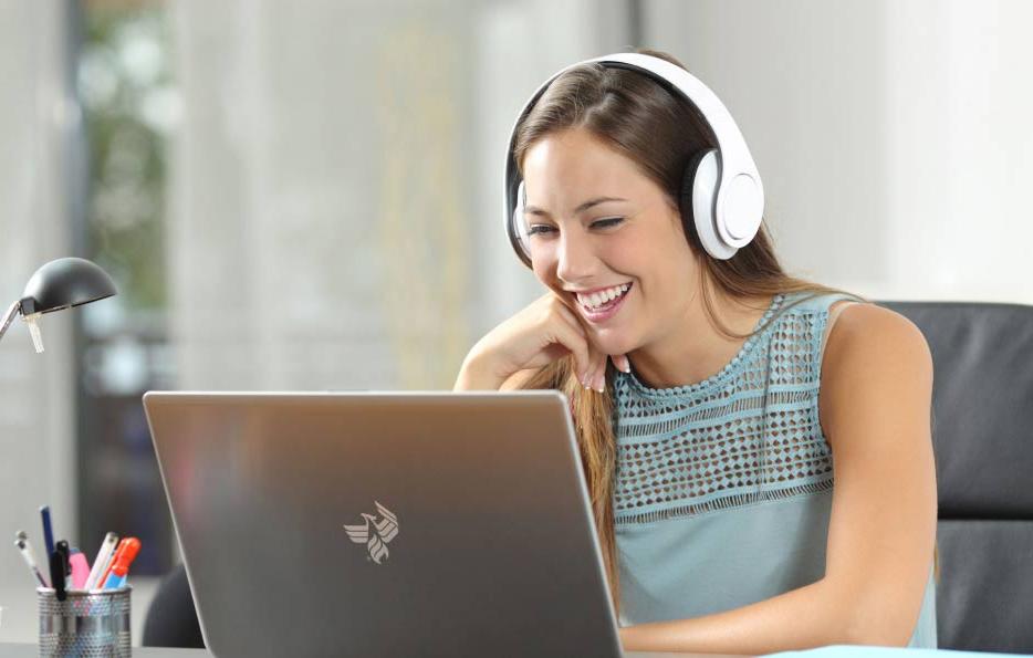 一位戴着耳机使用笔记本电脑的微笑女性
